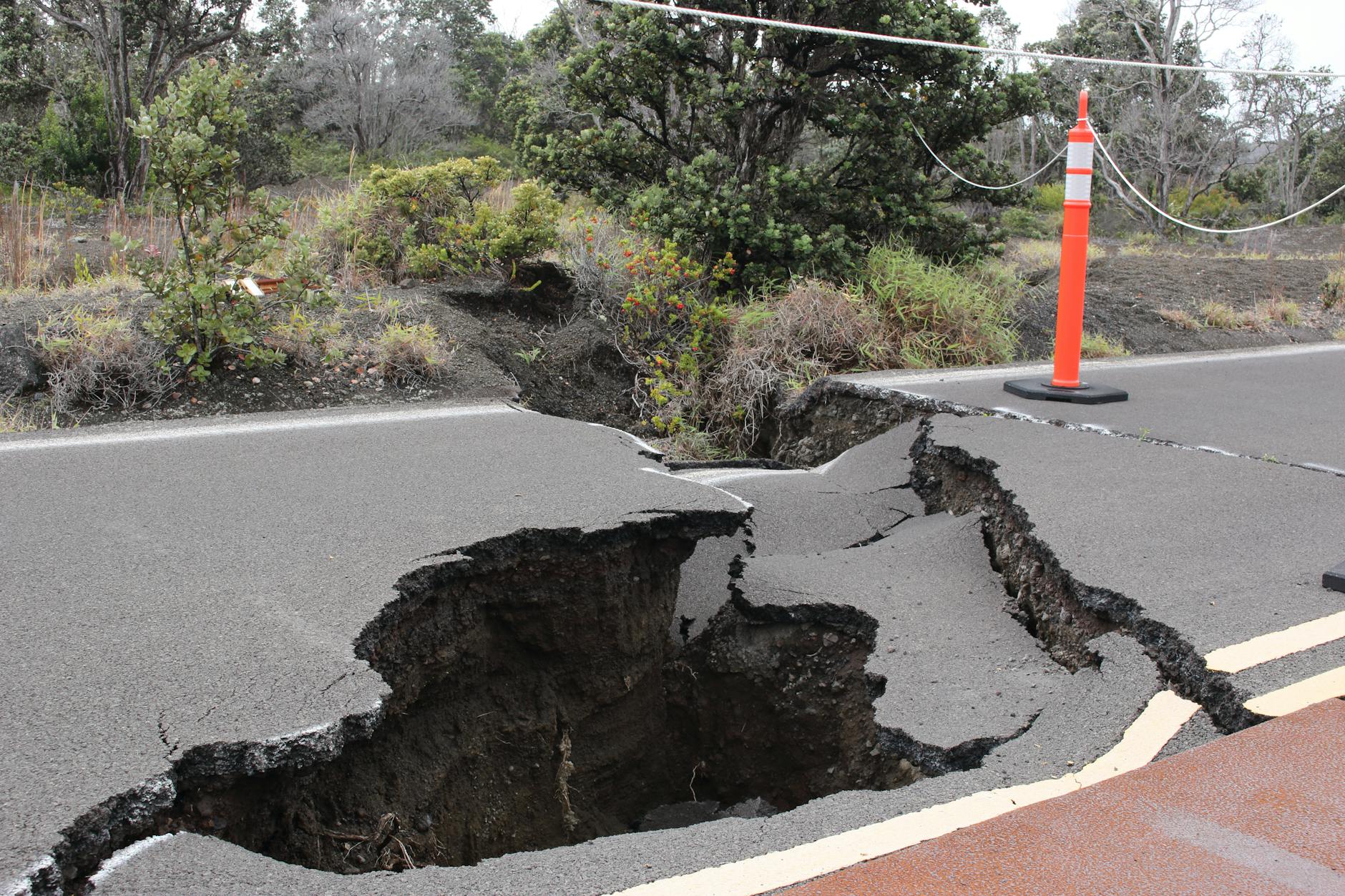 orange and white traffic pole on cracked gray asphalt road